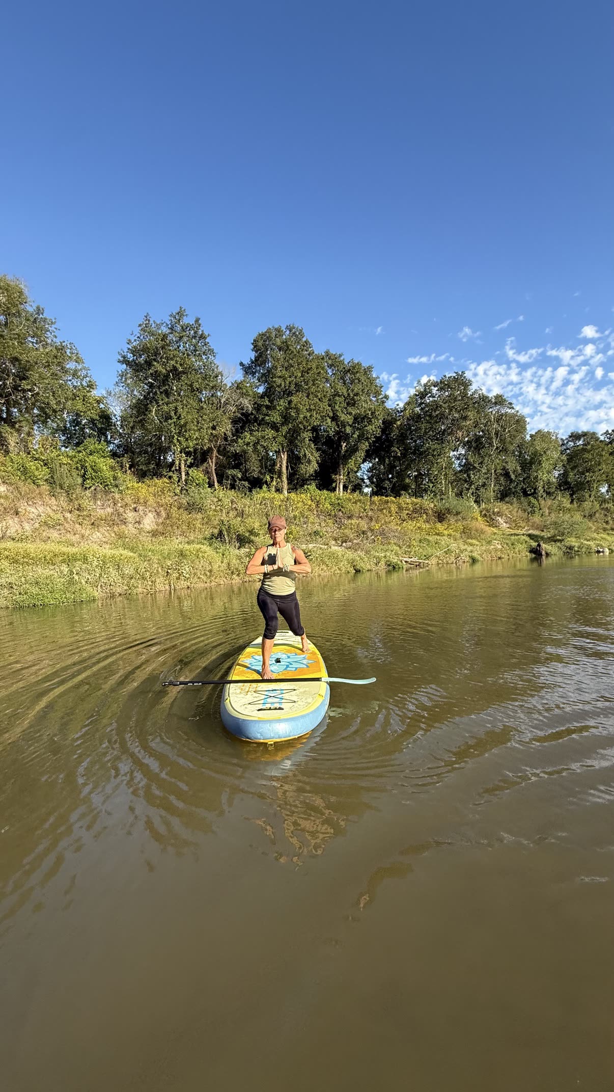 Paddleboard yoga on the river — hands at heart